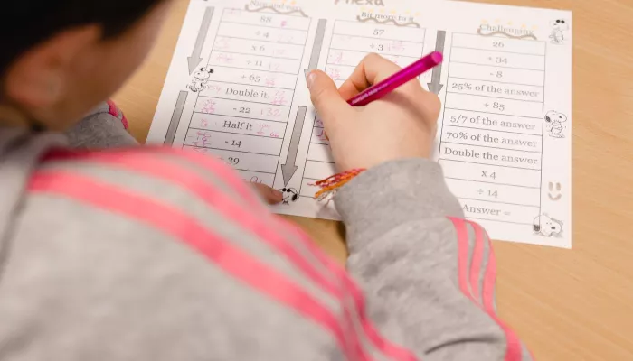 A pupil works on a writing activity in an exercise book