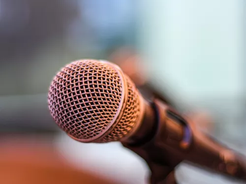 A close-up image of a microphone against a blurred background.