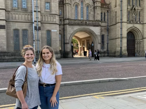 Alumna tutor Maddy and her mother standing outside Whitworth Hall, The University of Manchester.
