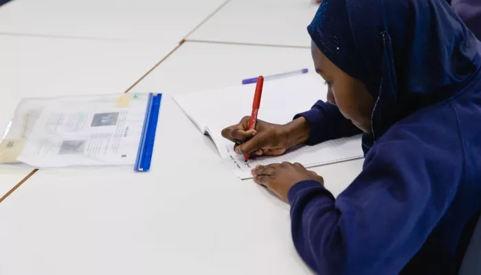 A pupil writes in an exercise book