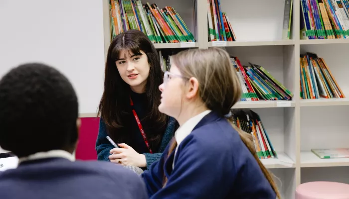 Female tutor smiles as pupil studies