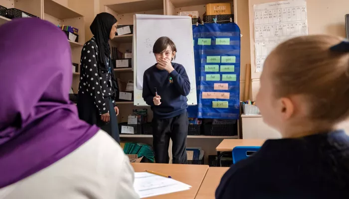 A young boy stands at the front of the group and is stifling a giggle and obviously enjoying the session.