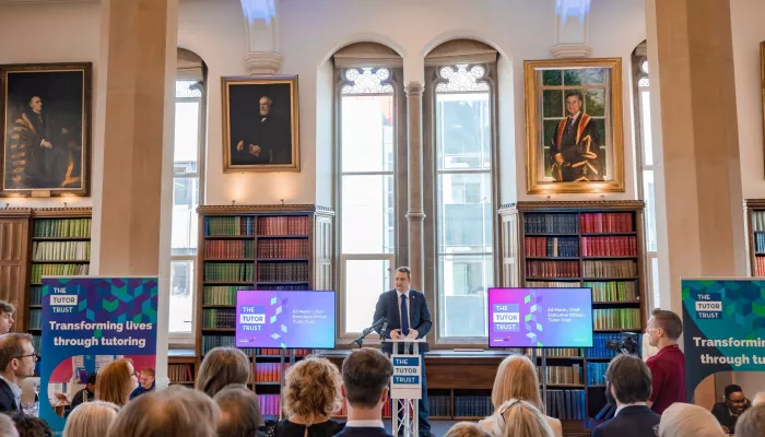 CEO Ed Marsh is addressing guests at the Summer Reception. He is standing at a lectern, in front of a large window, flanked by two bookcases.