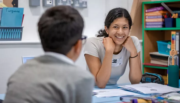 A tutor smiles at a young pupil