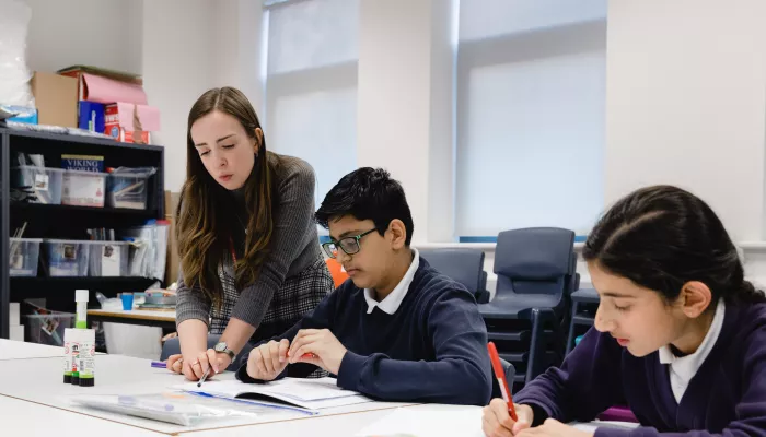 A tutor shows two pupils an exercise.