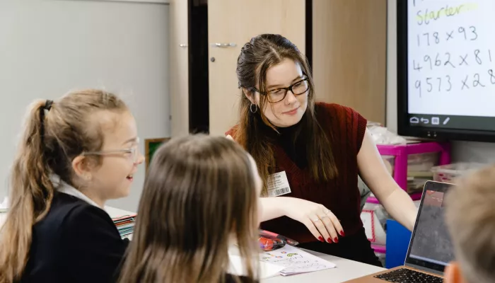 A tutor shows pupils how to work out a Maths question 