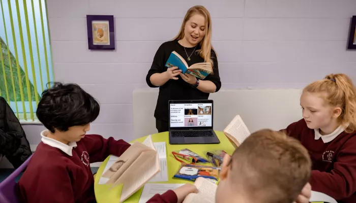 A tutor reads some text from a book to tutees