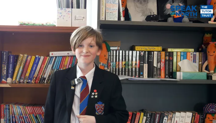 Pupil James wears a black blazer with several achievement badges on the sides, white shirt, and blue and red striped tie. He excitedly tells us how it feels to be a competition winner.