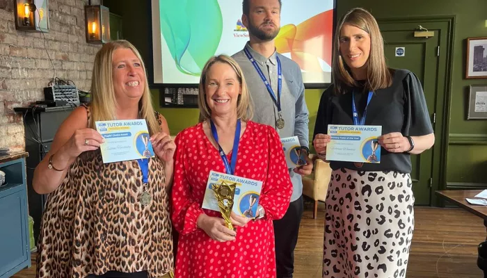 Three women and a man wearing medals hold certificates and smile