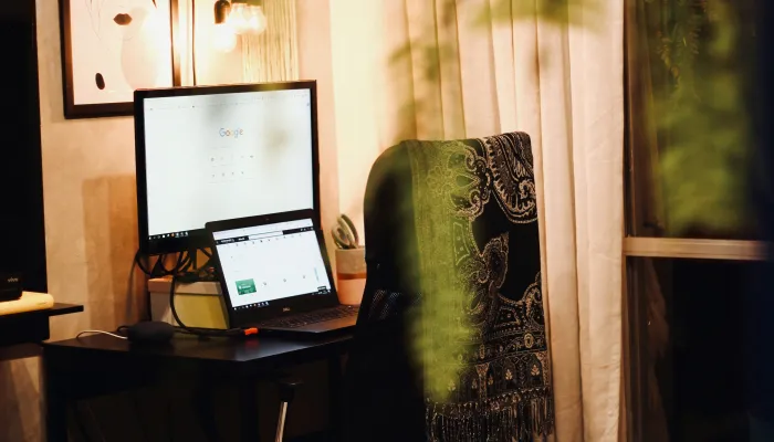 a desk with computer screens and a chair with a shawl represent a home office