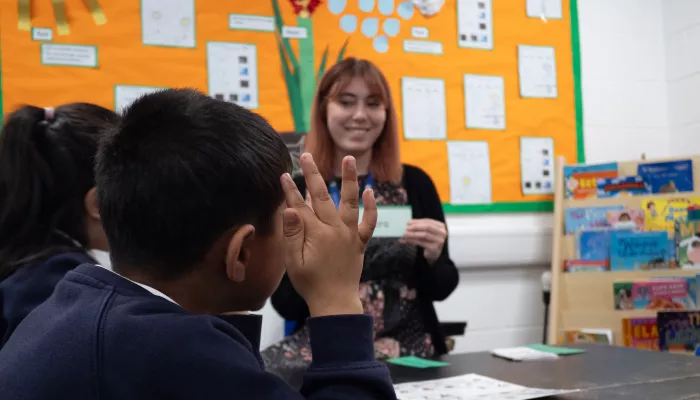 A pupil raises his hand to pronounce a phonics sound.