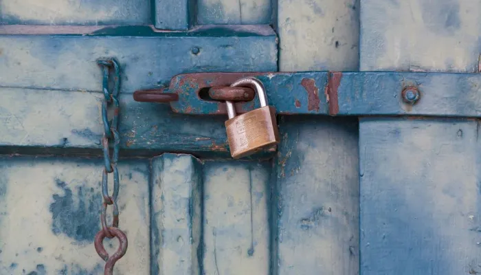 a brass padlock on a worn blue painted door