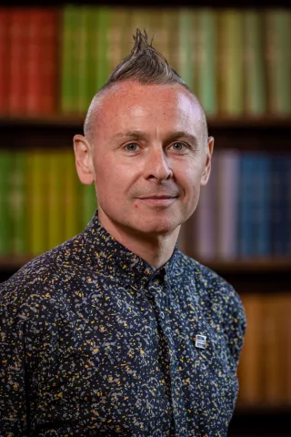 Robbie is focused on transforming the digital future of Tutor Trust, so that we can better serve our pupils and school partners, and make it easier for them to collaborate with us. Robbie is standing in front of a bookcase.  He is wearing a dark shirt. 