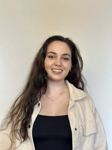 Hannah Cunningham is a former teacher who enjoys making a positive impact on young people's lives.  Hannah has long brown hair and is wearing a black jumper.