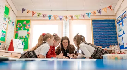 A tutor and pupils are enthusiastically studying some writing.