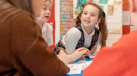 A pupil is smiling and looking eagerly at the tutor during a tuition session.