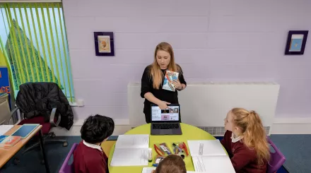 A tutor shows a group of pupils a page on a website relevant to their work