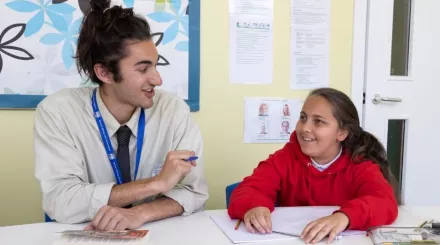 A tutor and pupil are smiling during a reading tuition session