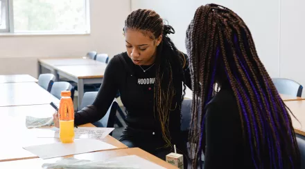 A student sits at a desk with a tutor 