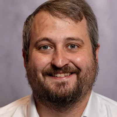 Chief Executive Officer Ed Marsh, is a powerful advocate for social mobility and championing the rights of those who are underserved. He is pictured wearing a white open-necked shirt, and is smiling to camera.