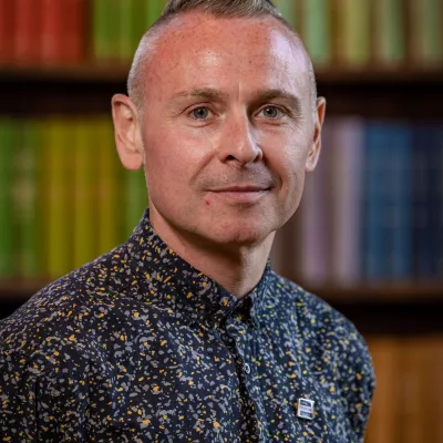 Robbie is focused on transforming the digital future of Tutor Trust, so that we can better serve our pupils and school partners, and make it easier for them to collaborate with us. Robbie is standing in front of a bookcase.  He is wearing a dark shirt. 