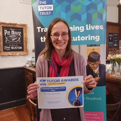 A woman smiles and holds a certificate