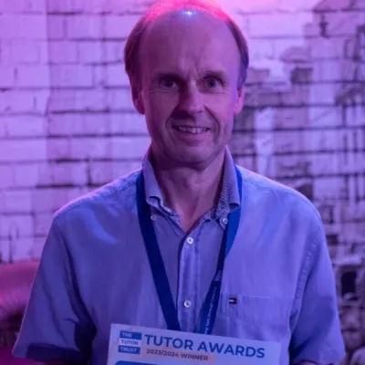 A man in a blue shirt holds a winner's certificate 