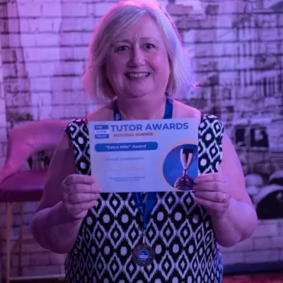 A blonde woman smiles and holds a winner's certificate