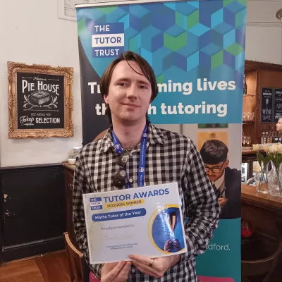 A man in a checked shirt holds a certificate