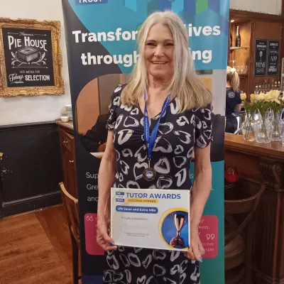 A woman in a dress smiles and holds a certificate