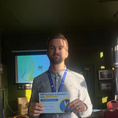 A man in a blue shirt holds a winner's certificate 