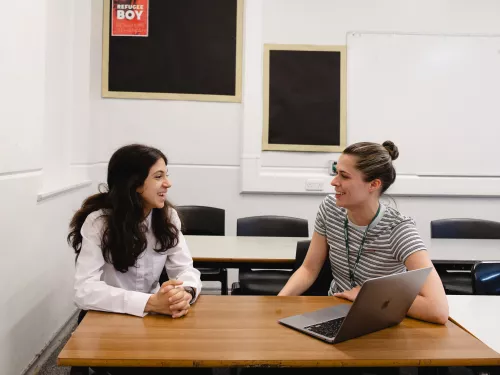 A tutor and a pupil smile during a tuition session.