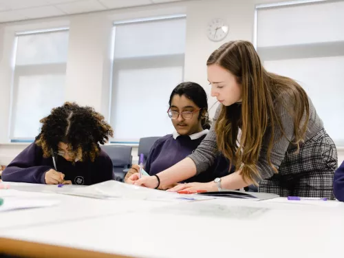 A tutor shows some writing to two pupils