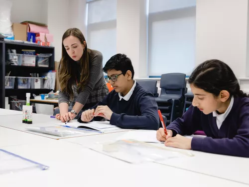 A tutor shows two pupils an exercise.