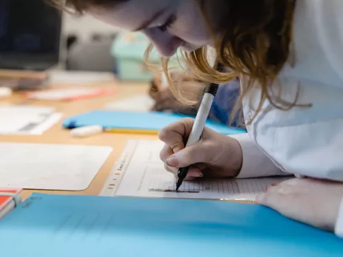 A child writes in an exercise book during a tuition session.