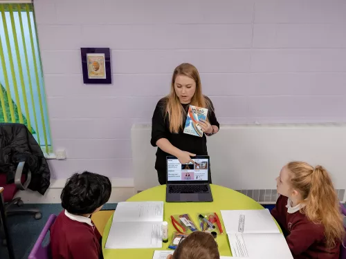 A tutor shows a group of pupils a page on a website relevant to their work