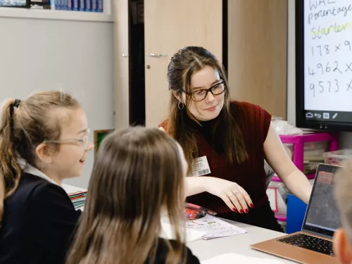 A tutor shows pupils how to work out a Maths question 