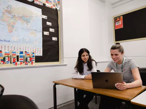 A tutor and a pupil work together, and are both looking at some content on a laptop