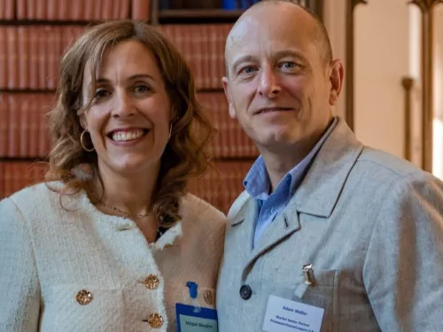 Abigail Shapiro from Tutor Trust wears a white jacket and stands alongside Adam Waller from PwC who wears a blue shirt and grey jacket 