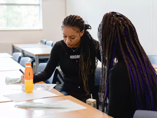 A student sits at a desk with a tutor 