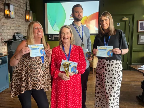 Three women and a man wearing medals hold certificates and smile