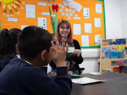 A pupil raises his hand to pronounce a phonics sound.