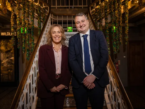 Tutor Trust Co-founder Abigail Shapiro and CEO Ed Marsh stand at the foot of a flight of stairs in Manchester Museum.